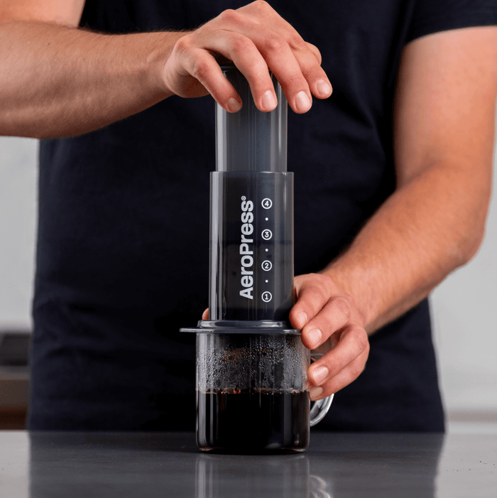A barista making a coffee with an aeropress portable coffee maker