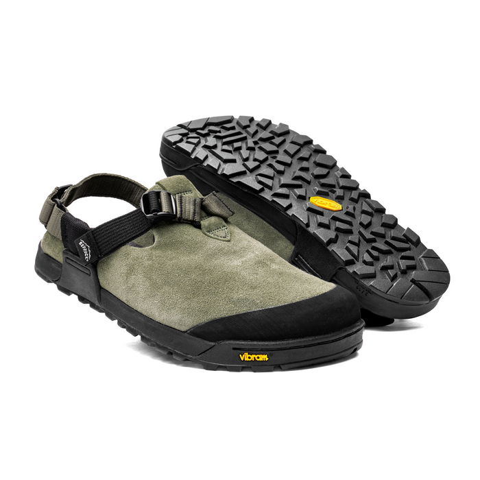 A pair of Bedrock Mountain Clogs with suede leather upper and a black Vibram Megagrip outsole. One clog is turned to show the strap system, and the other is placed upright to display the sole.