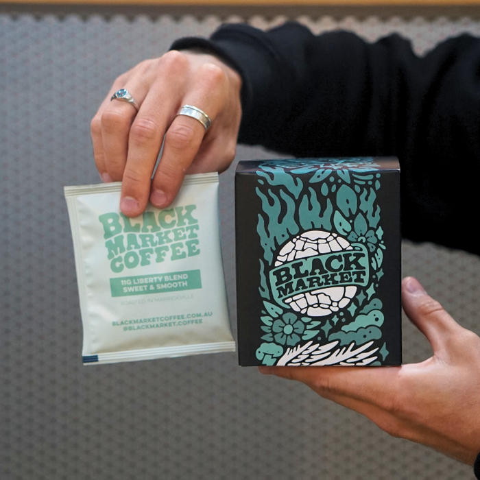 A black Market Coffee drip bag and the box of ten packaing on a grey background