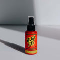 A red spray bottle labeled 'Bug Grrr Off' on a shadowy background, indicating a natural insect repellent.