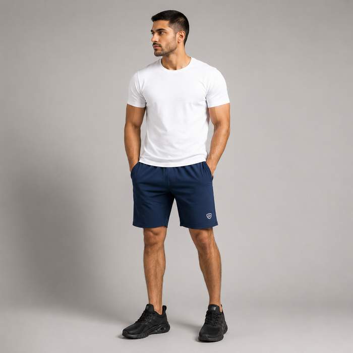 A man wearing a high quality navy blue athletic shorts stretchable material with a small white Dominance logo on the left leg, and black sneakers, standing