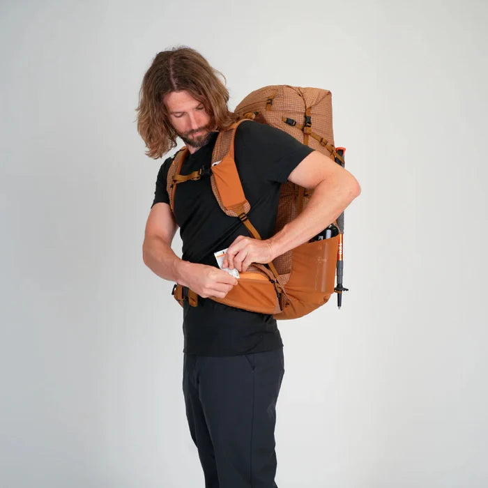 Man with a large brown backpack on a plain background