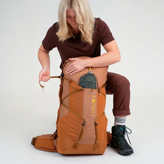 Person sitting with a large brown backpack on a white background
