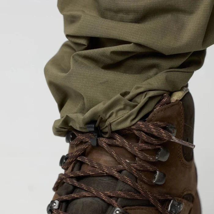Brown leather boots worn with green pants on a white background