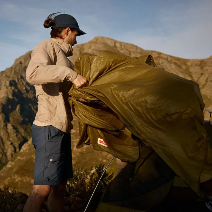 Person setting up a tent in a mountainous landscape