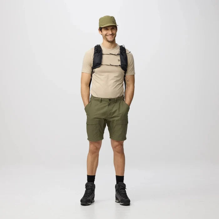 Person wearing a beige shirt, green shorts, and a green cap with a backpack on a white background