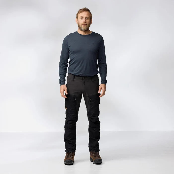 Man wearing a dark long-sleeve shirt and black pants on a white background