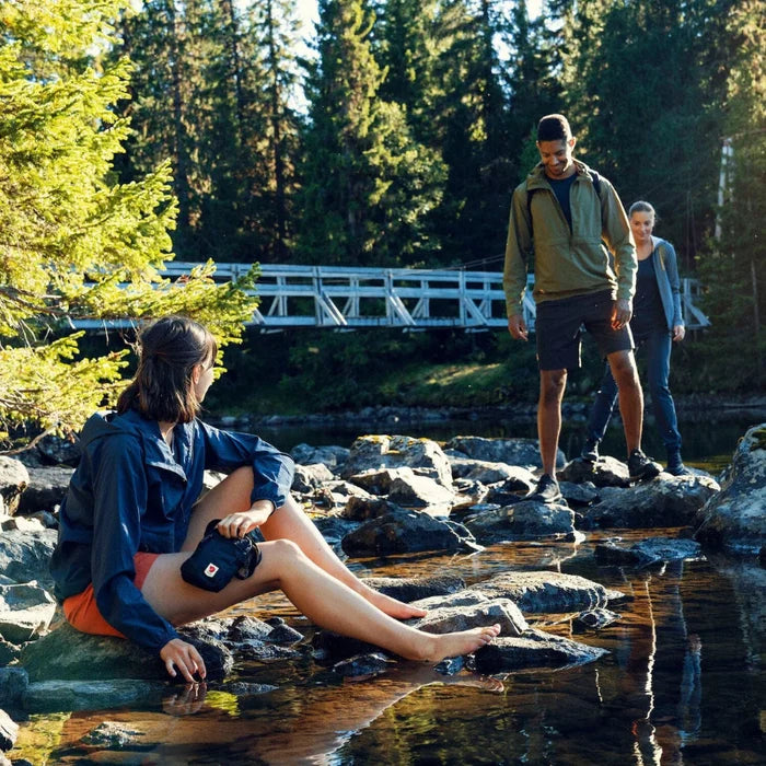 People enjoying a day at a lakeside with a bridge and trees in the background
