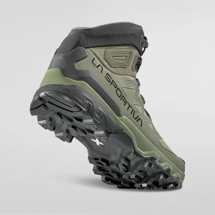 Green and black hiking boot with 'La Sportiva' branding on a light gray background