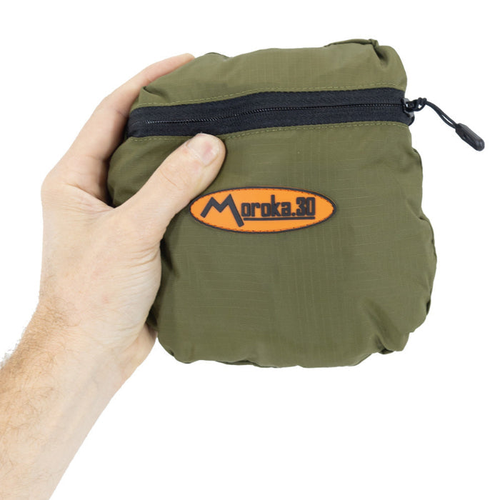 Green pouch with a zipper held by a hand, featuring the Moroka 30 logo.