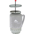 An MSR Coffee press on a windburner stove on a white backround