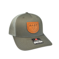 A green PAST Outdoors trucker's hat with an orange brand patch on the front, featuring a pre-curved visor and an adjustable snapback.