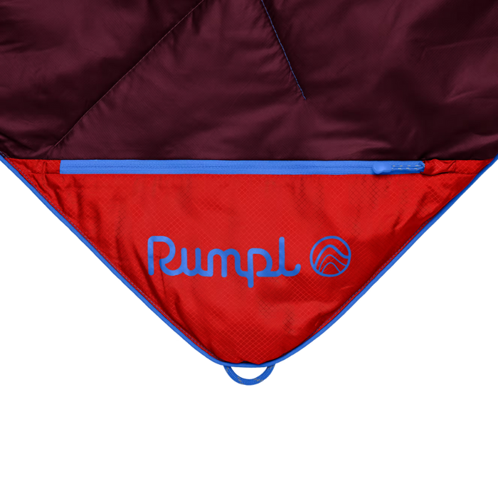 Close-up of a camping sleeping bag or tent showing the red interior with blue piping and the blue embroidered Pumpl logo, against a white background.