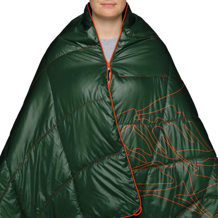 A close-up of a person wearing a dark green puffer-style sleeping bag or wrap with bright orange zipper trim and orange topographic contour line graphics on the front, against a plain white background.