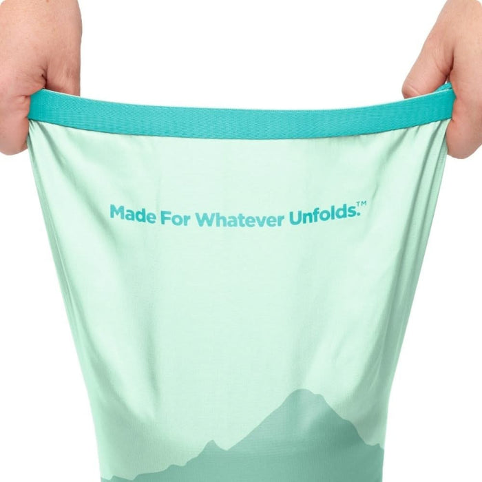 Light green mesh bag with 'Made For Whatever Unfolds' text held by hands on a white background