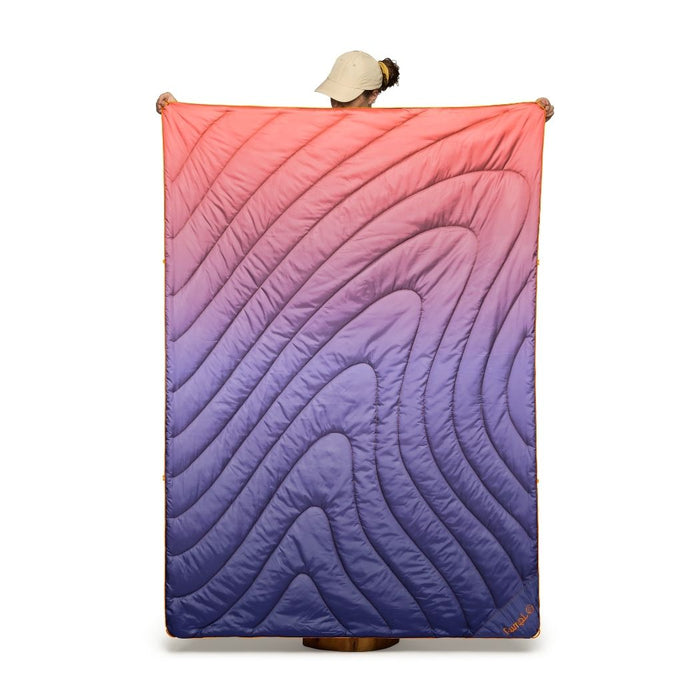 Person holding a colorful quilt with a gradient pattern on a white background