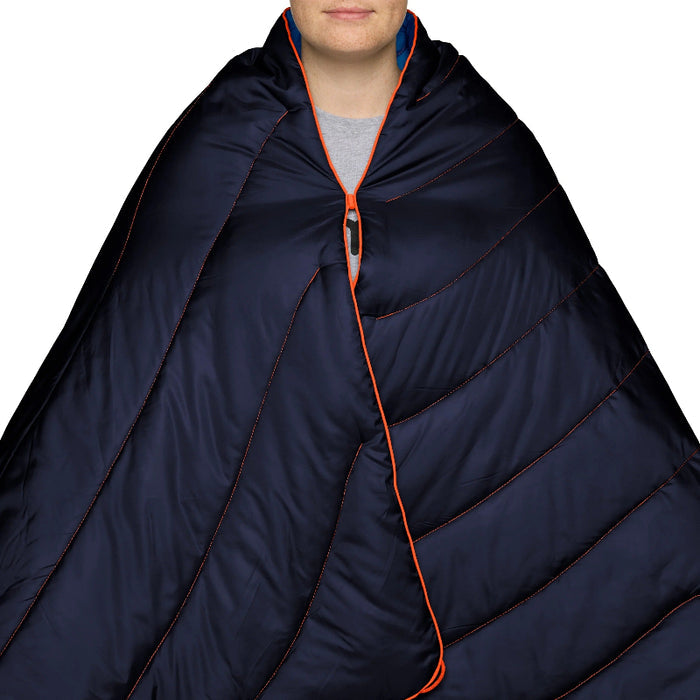 Person wearing a navy blue sleeping bag with orange zipper on a white background