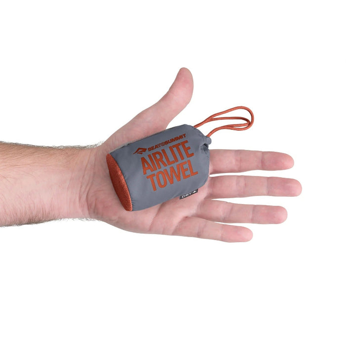 Hand holding a compact airlight towel against a white background