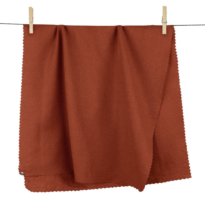 Brown fabric hanging on a clothesline with wooden clips against a white background