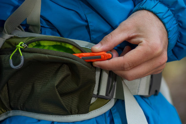 A person pulling our a ferrocium rod out of their bag pocket