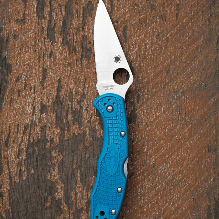 Folding knife with a blue handle on a wooden surface