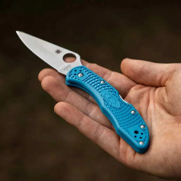 Hand holding a blue folding knife with a blurred background